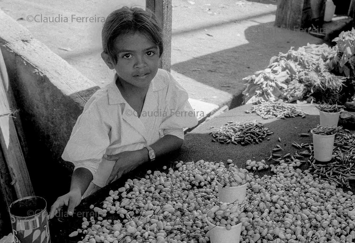 Menina vendendo pimentas em uma barraca de mercado